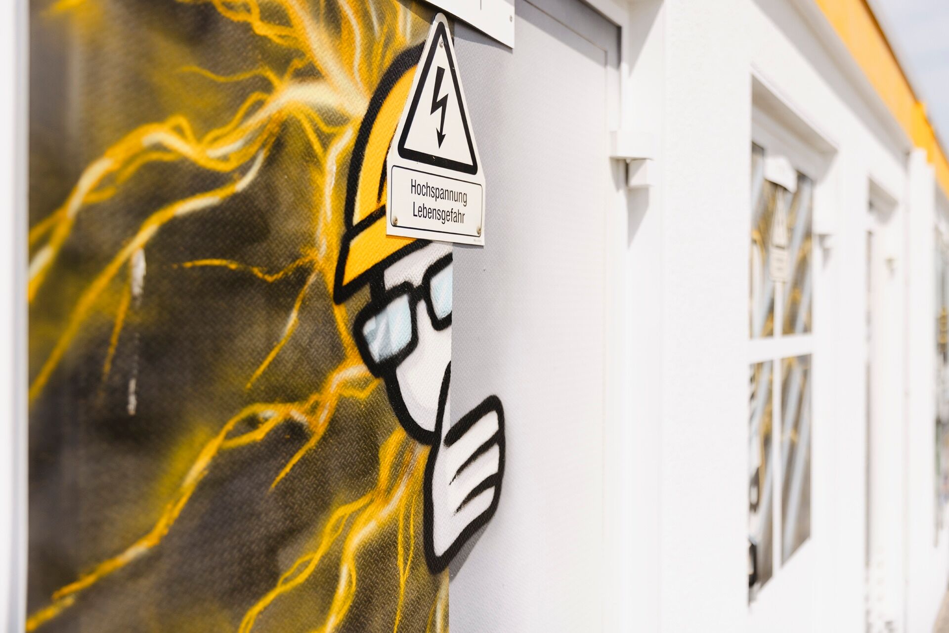 Graffiti eines Bauarbeiters mit Helm, um den elektrische Blitze schweben und der um die Ecke einer Tür schaut
