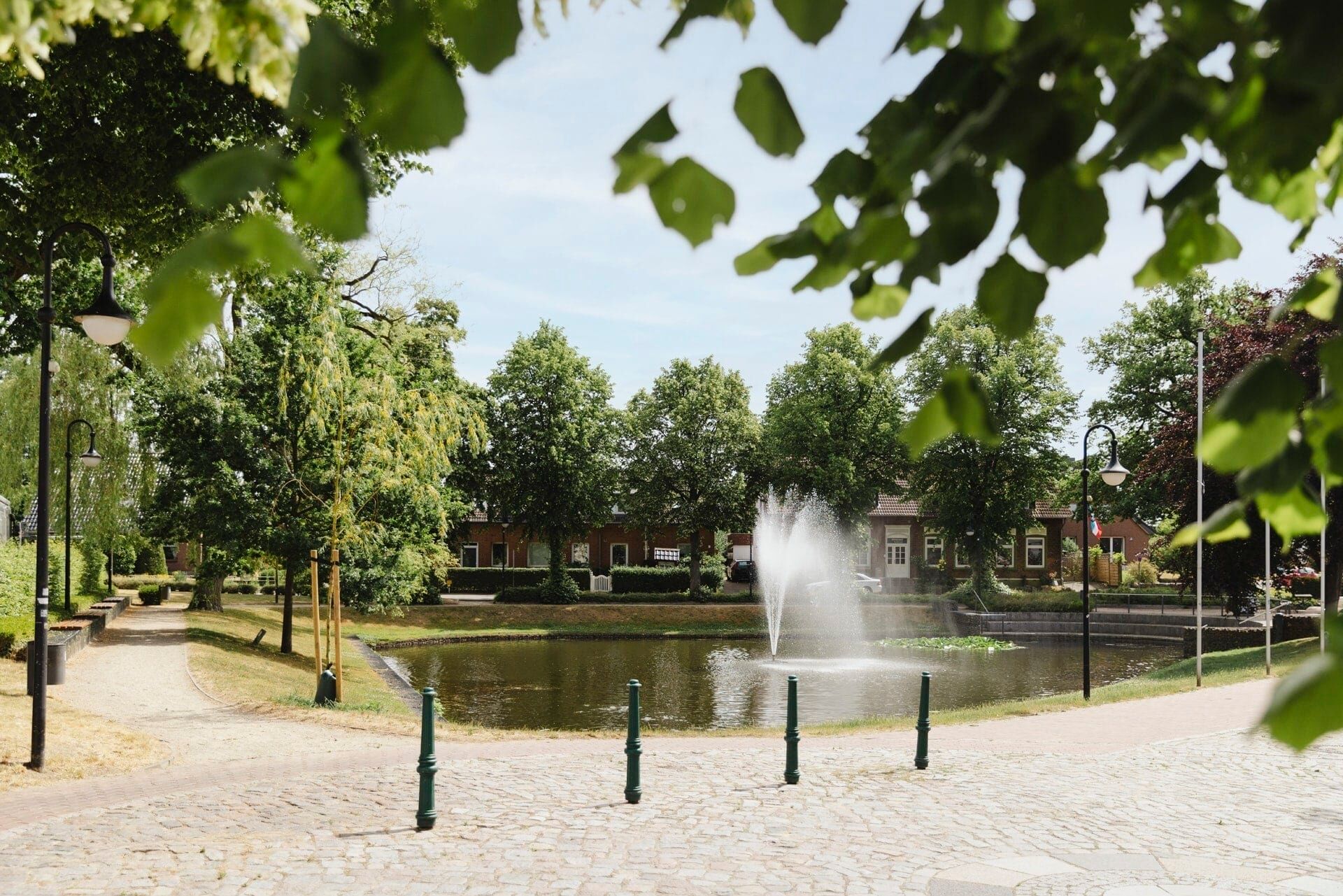 Dorfteich mit Springbrunnen, um den ein Spazierweg führt, in Schönkirchen